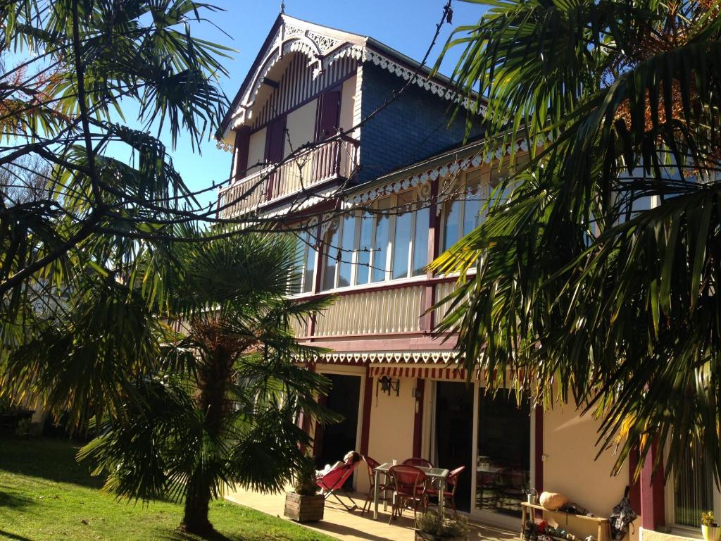 un bâtiment avec un palmier en face dans l'établissement Chalet des Palmiers, à Bagnères-de-Bigorre