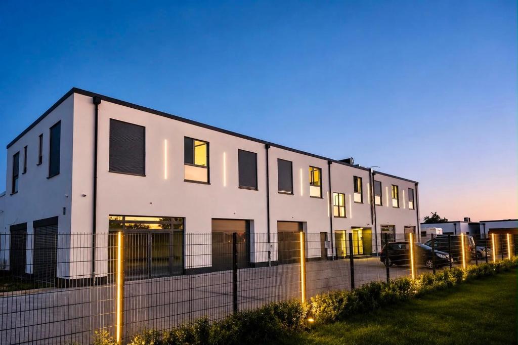 a white building with a fence in front of it at StayIN Suites in Griesheim