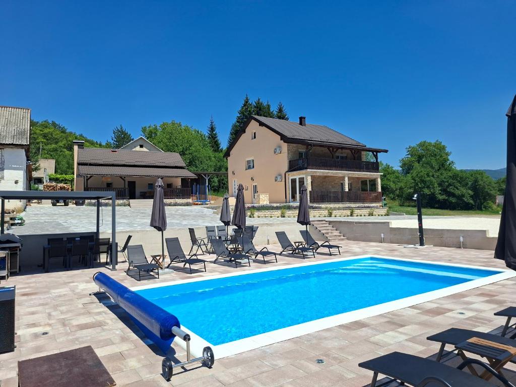 a swimming pool with chairs and a house at Jakiland house Plitvice Lakes in Korenica