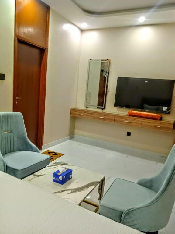 a room with two chairs and a flat screen tv at The R Hotels Nursery in Karachi