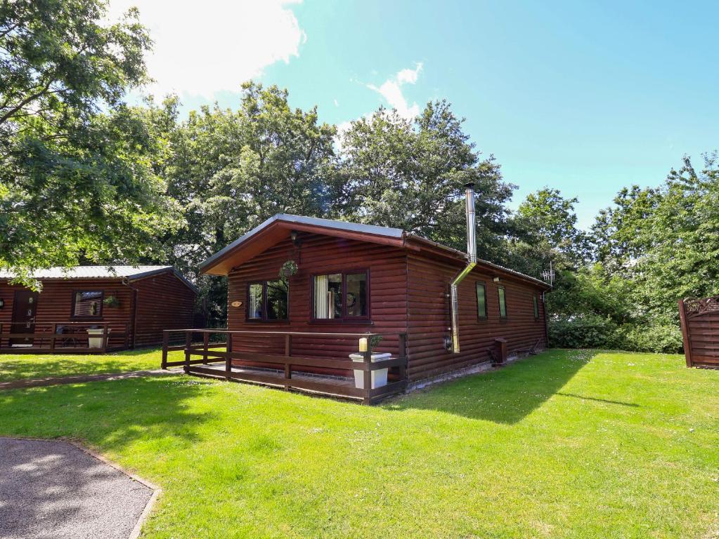 a log cabin in a yard with a green lawn at The Red in St Asaph