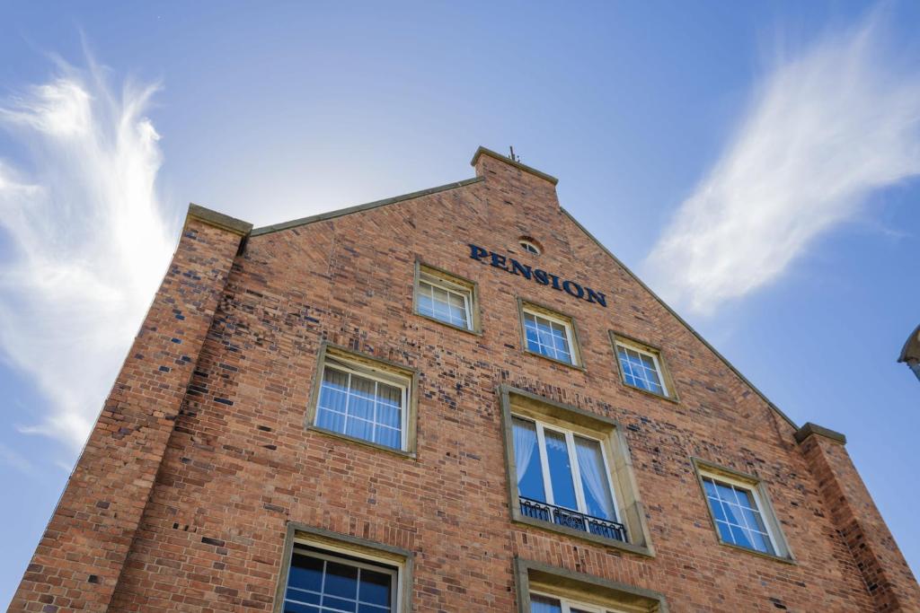a brick building with a sign on the top of it at Pension Zur Inselbrücke in Wolgast