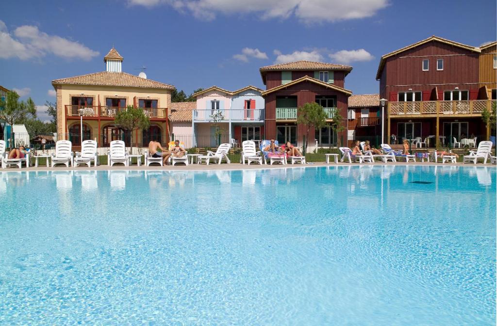 uma grande piscina com cadeiras e pessoas sentadas em cadeiras em Madame Vacances Les Rives Marines em Le Teich