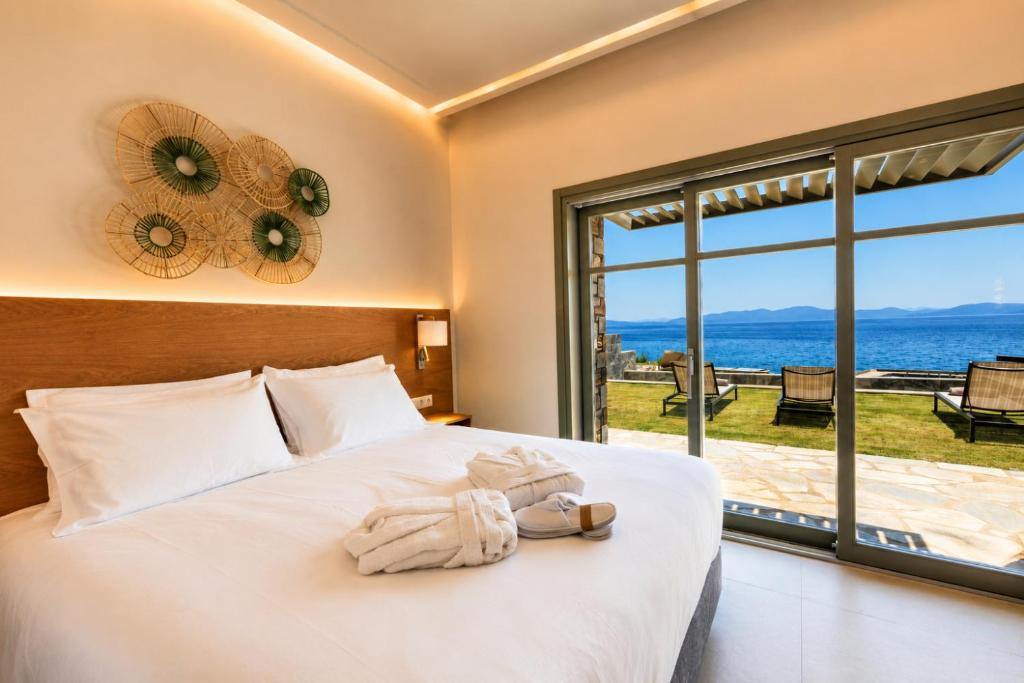 a bedroom with a bed with a view of the ocean at LEOLIA Nautical Resort Kala Nera - Handwritten Collection in Volos