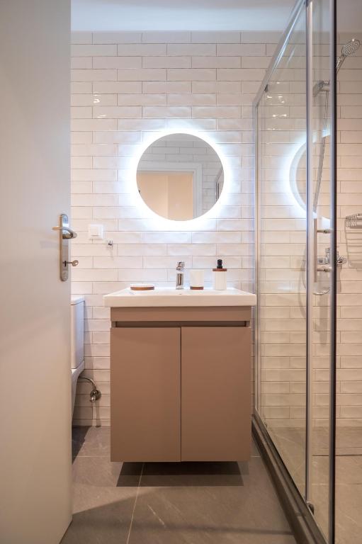 a bathroom with a sink and a glass shower at Perla Port Suites in Chios