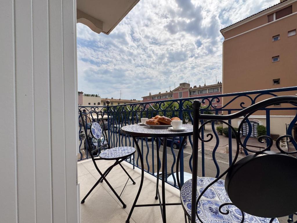 ein Balkon mit einem Tisch und einem Teller mit Essen darauf in der Unterkunft EASY Tropez in Grimaud
