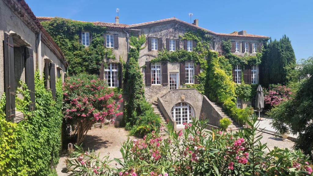 an ivy covered building with flowers in front of it at Château de Floure - SPA et piscine extérieure chauffée in Carcassonne