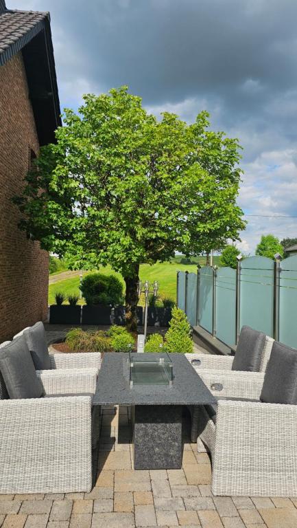 a patio with a table and two couches and a tree at Auszeit Eifel Ihre private Auszeit zu zweit in Reuth