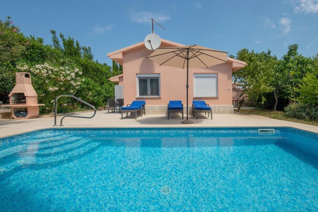 a villa with a swimming pool and an umbrella at House Nada 1201 in Banjole