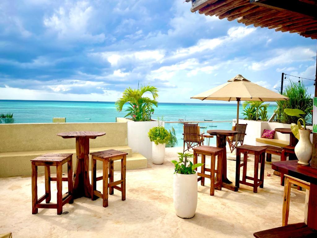 a patio with tables and chairs and the ocean at Aluna Beach Apartments in Nungwi