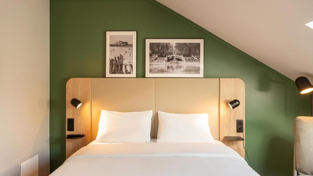 a bedroom with a green wall with a bed at Campanile NATURE - Vannes in Vannes
