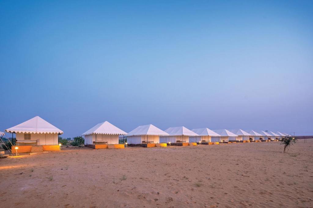 a row of white tents on a sandy beach at Quba Desert Camp Jaisalmer in Jaisalmer