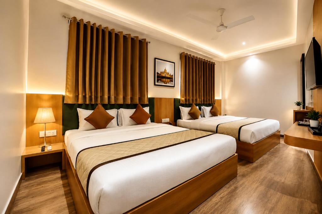 two beds in a hotel room with curtains at Hotel Nayyar Regency Near Golden temple in Amritsar