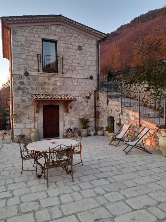 a stone patio with a table and chairs in front of a building at Dimora del Capriolo in San Donato Val di Comino