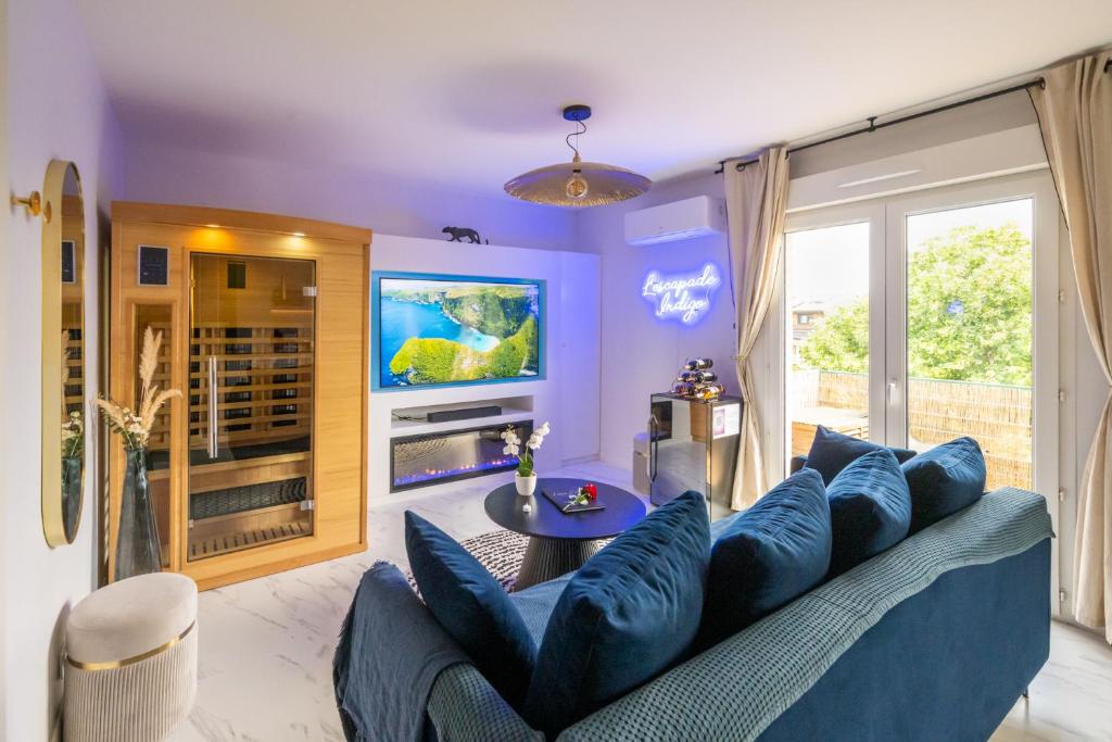 a living room with a blue couch and a tv at L'Escapade Indigo - Balnéo - Sauna in Tournefeuille