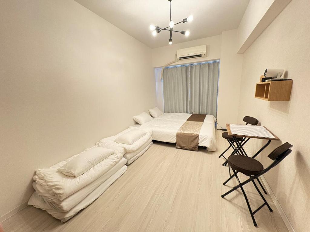 a bedroom with a bed and a table and chairs at Stay min NAKAMURA in Nagoya