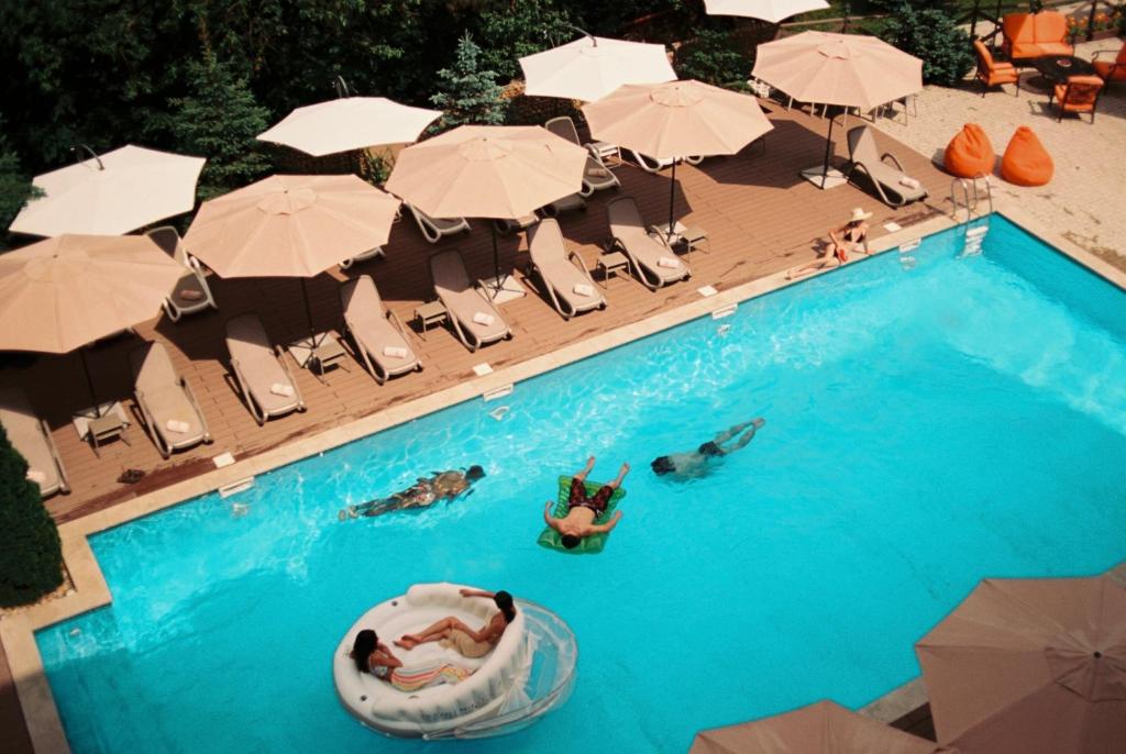 a pool with people on a raft in the water and umbrellas at Best Western Plus Paradise Hotel Dilijan in Dilijan