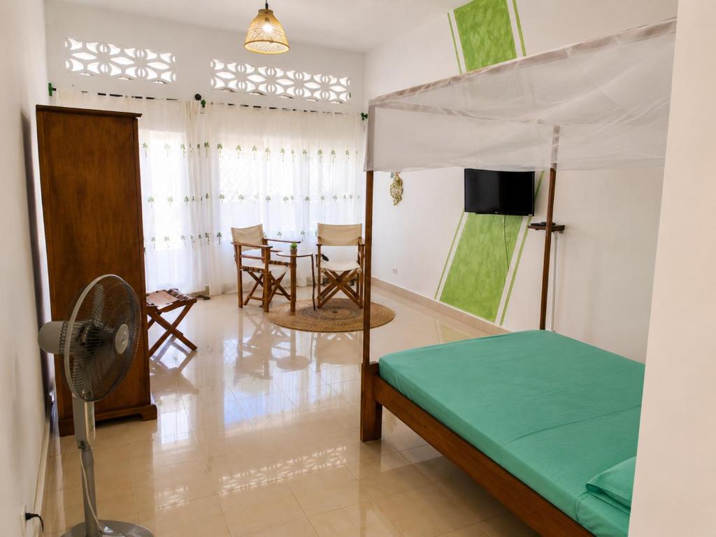 a bedroom with a bed and a table and chairs at Studio Poivre - Séjour tropical à Nosy Be in Madirokely