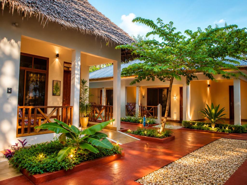 a house with a courtyard with trees and plants at Tumaini Bungalows in Nungwi