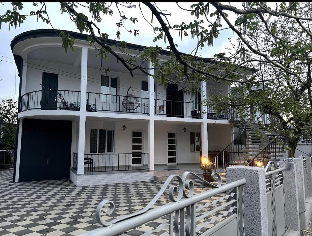 a large white house with a porch and a fence at Casa Bianca Kobuleti in Kobuleti