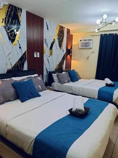 a hotel room with two beds with blue and white at Lis Urban Residence in Manila
