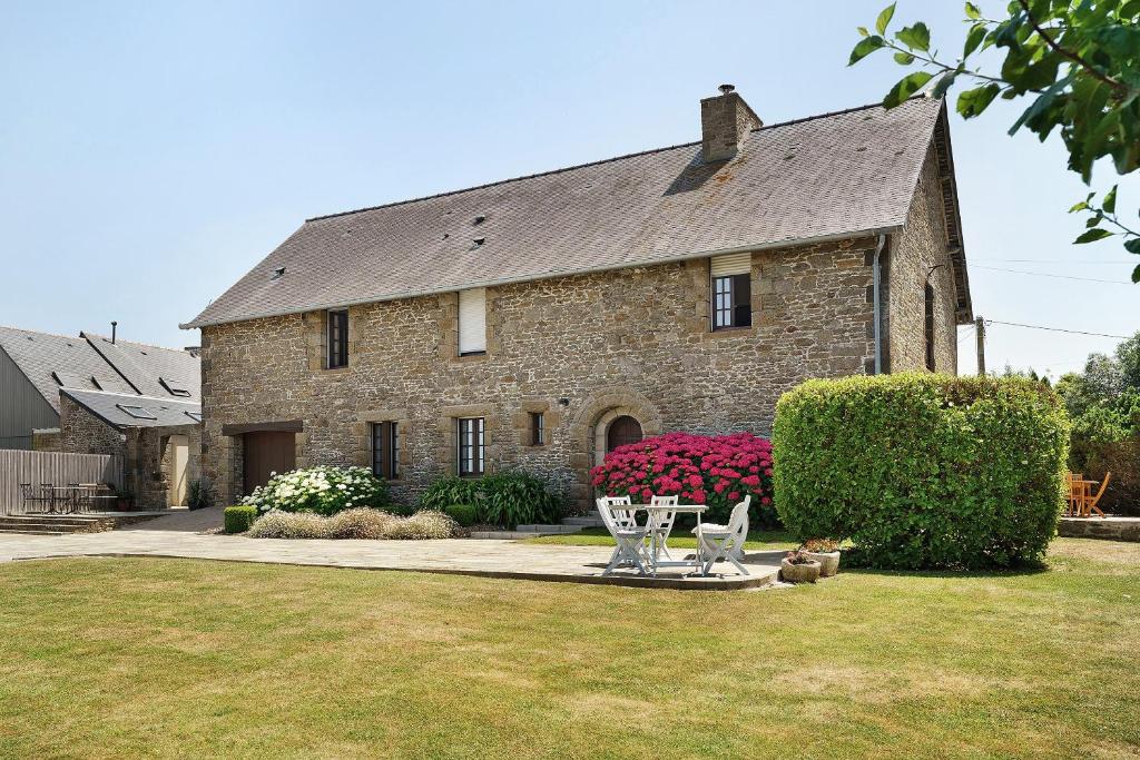 a large brick house with two chairs in a yard at L'aoûtienne - 300m de la plage in Saint-Coulomb