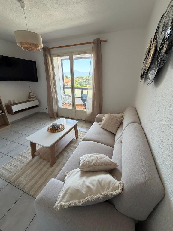 a living room with a couch and a table at Apartment - Beach - AC - Private parking in Saint-Cyprien-Plage