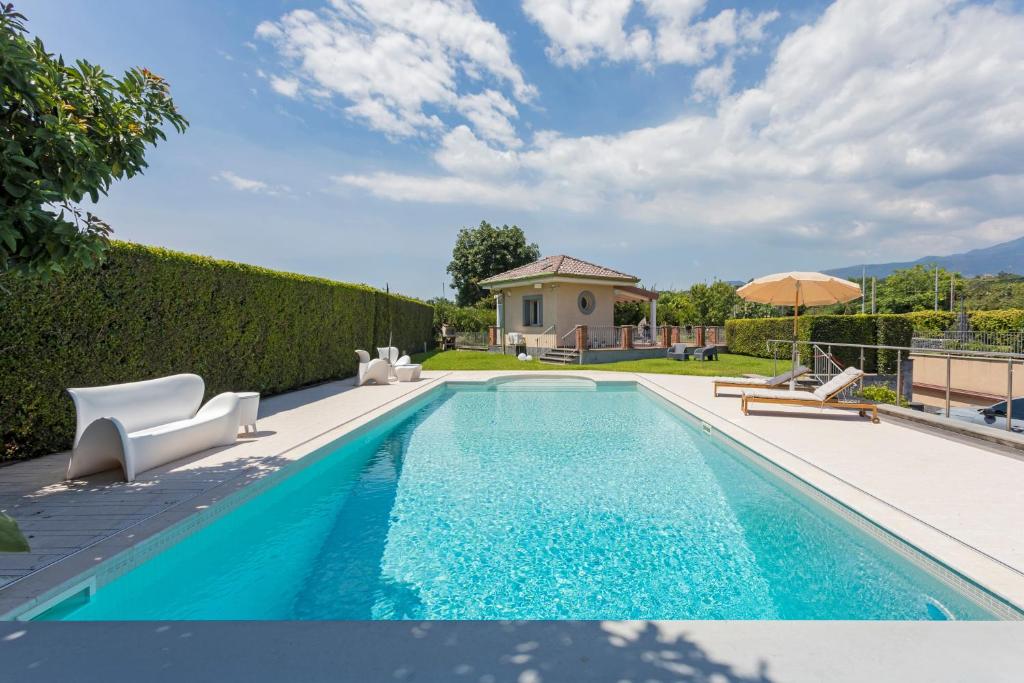 a swimming pool with chairs and an umbrella at Tropical House in San Leonardello