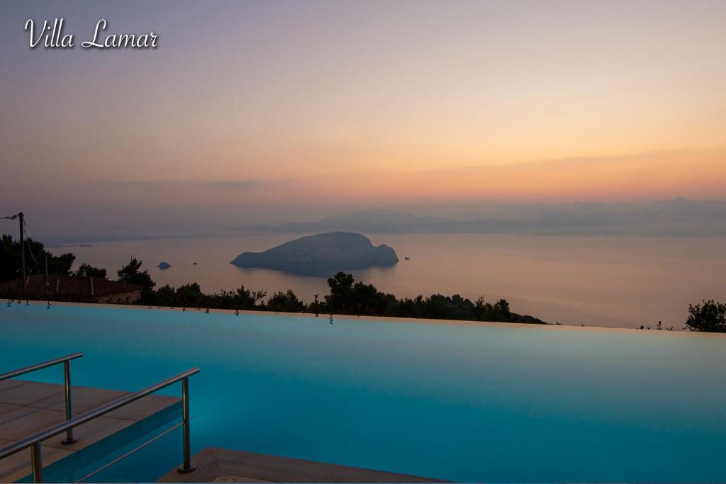 a pool with a view of the ocean at sunset at Villa Lamar Private Luxury Villa in Marathias