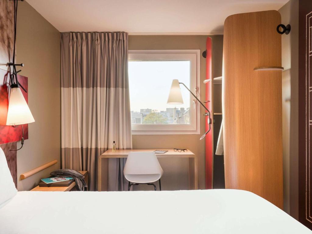 a bedroom with a bed and a desk and a window at ibis Le Havre Centre in Le Havre
