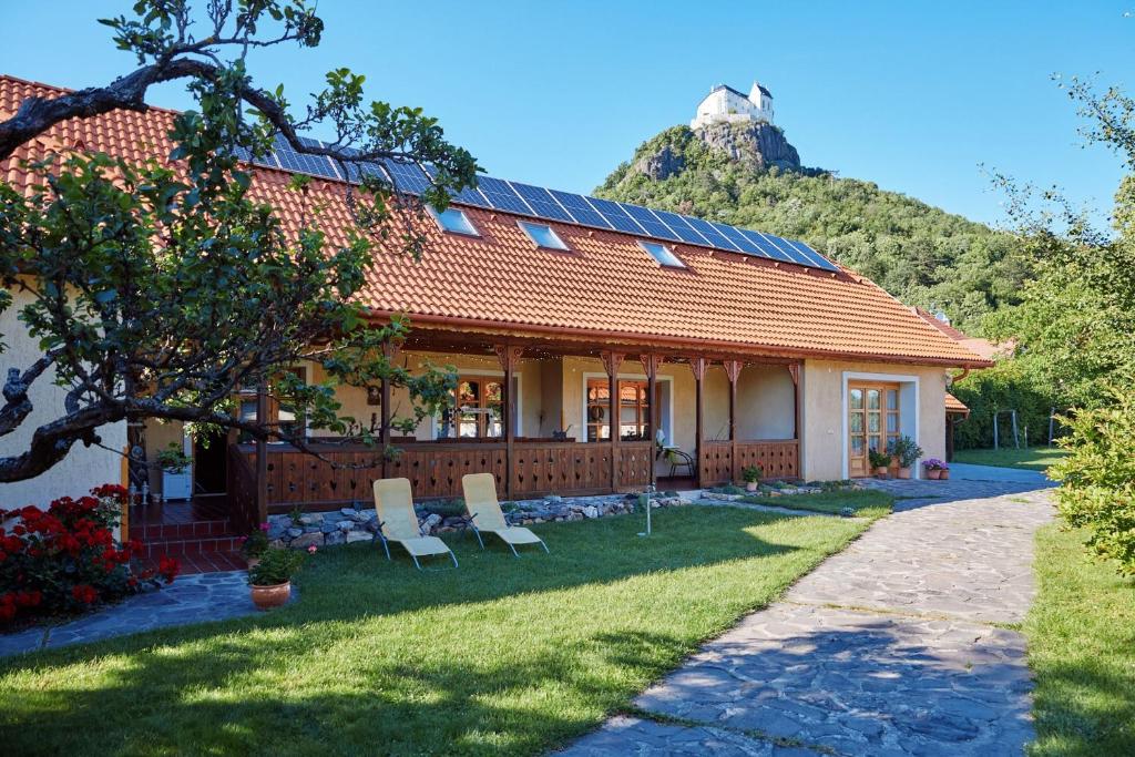 a house with two chairs and a mountain in the background at Borbála Vendégház in Füzér