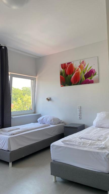 two beds in a room with a painting on the wall at Rosenhof am Main in Offenbach