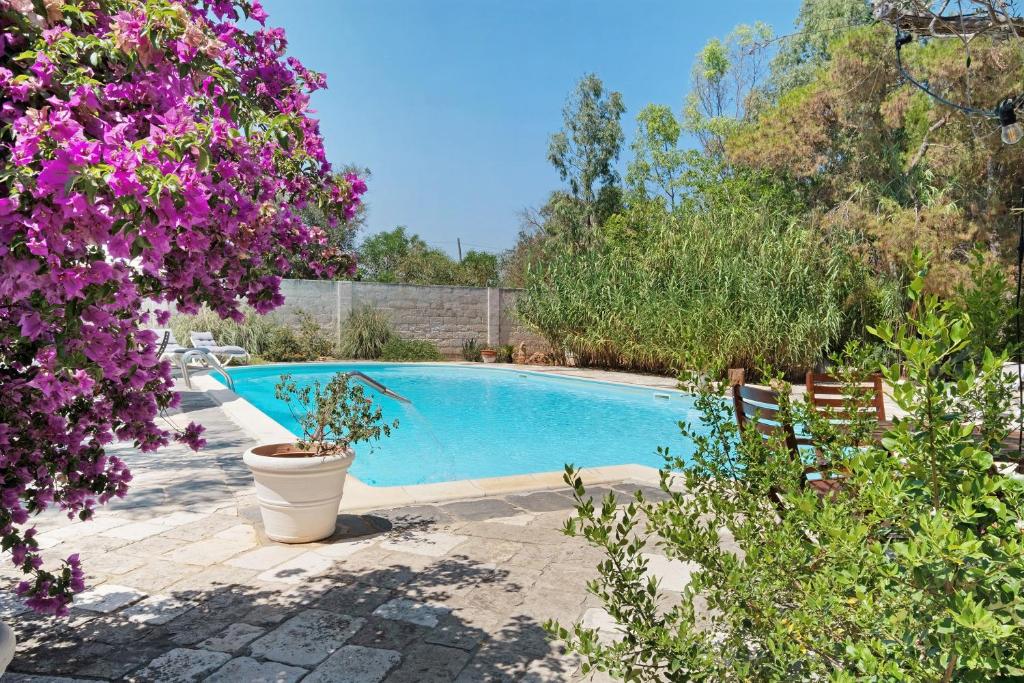 a swimming pool in a garden with purple flowers at Villa La Cucchiara in Santa Caterina di Nardò