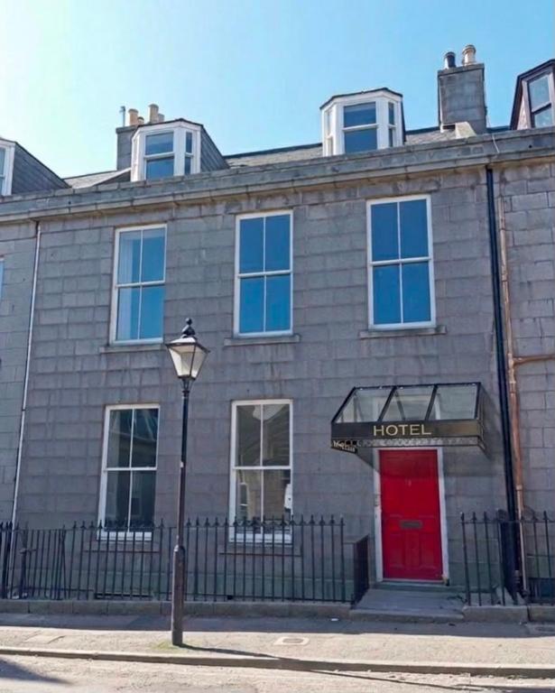 a brick building with a red door and a sign at Super Nova Self-Service Hotel in Aberdeen