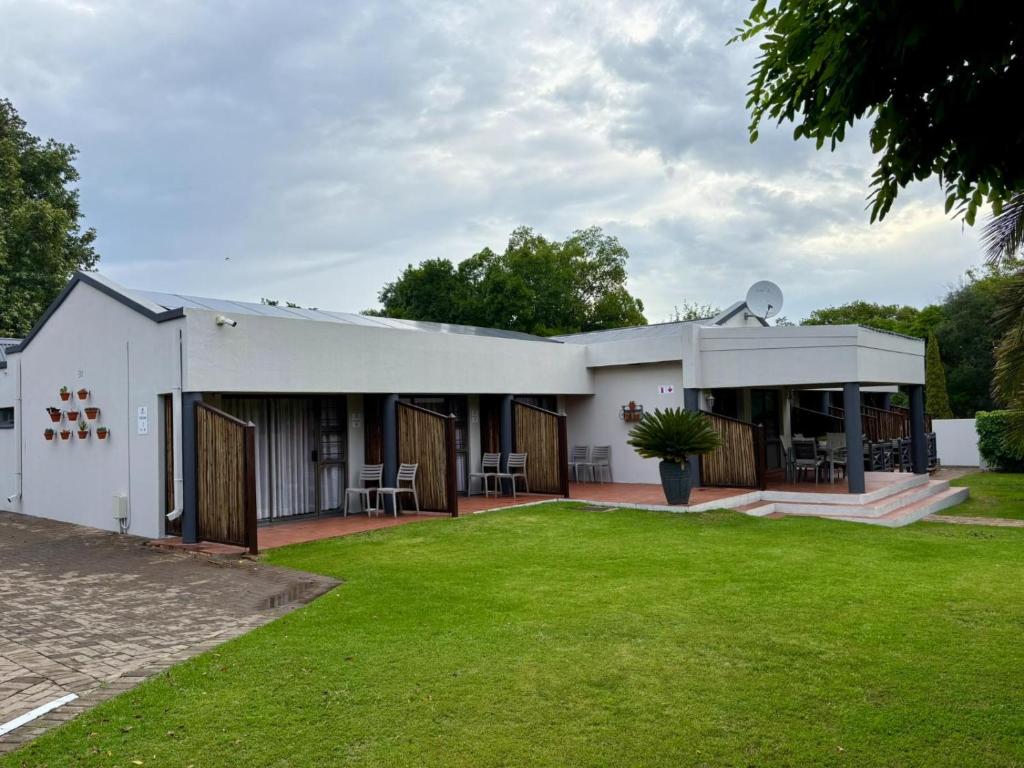 a white building with a lawn in front of it at The Suburban Guest House in Bloemfontein