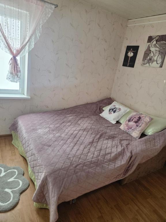 ein Schlafzimmer mit einem Bett mit lila Laken und einem Fenster in der Unterkunft Pas tetulę in Anykščiai