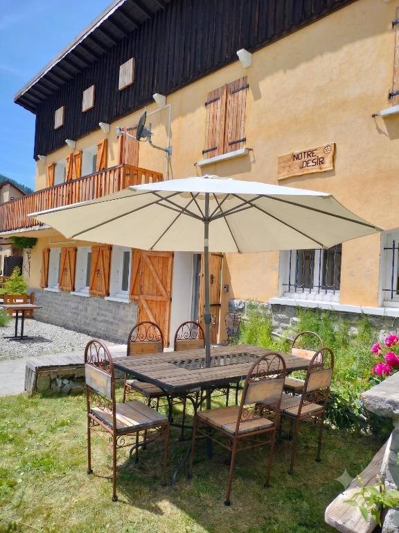 a table with an umbrella in front of a building at Gite Notre Désir in Abriès