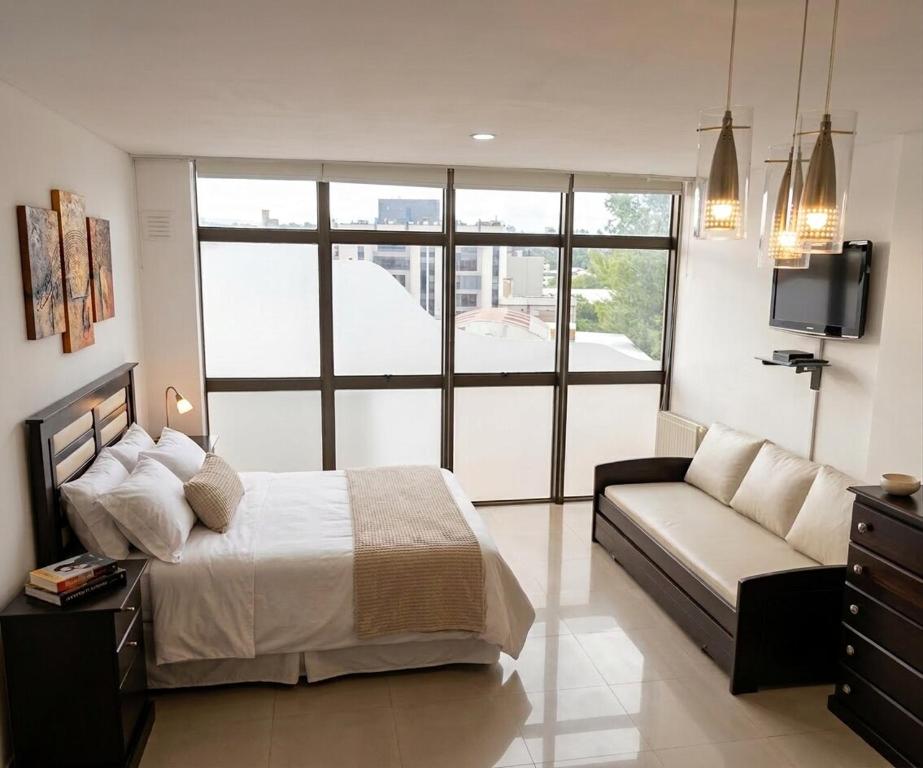 a bedroom with a bed and a couch and a tv at Torre Melos, 2do piso, centro, con cochera in Villa Carlos Paz