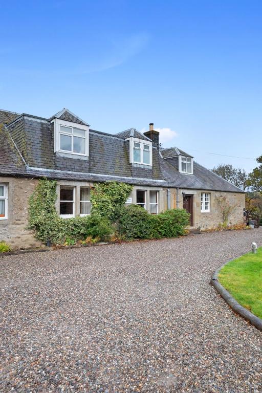 a house with a gravel driveway in front of it at Keepers Cottage in Dunkeld