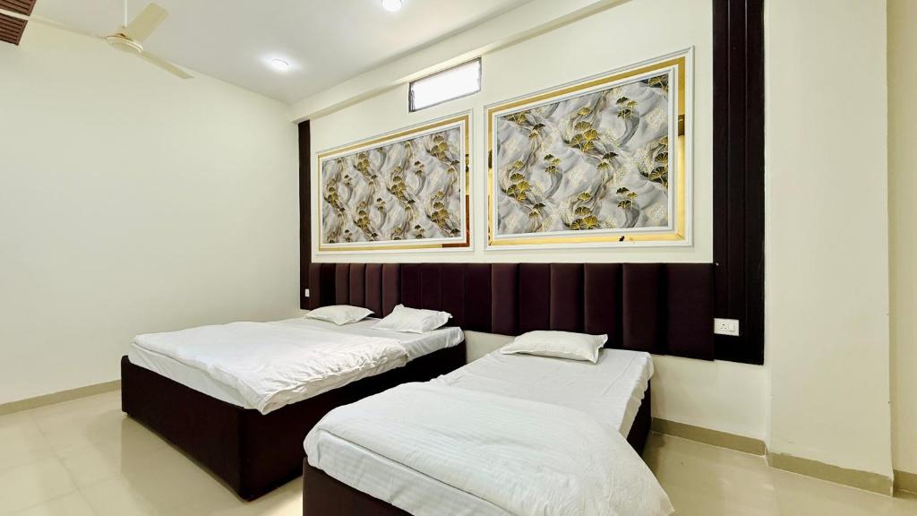 two beds in a room with paintings on the wall at Hotel Gurukripa in Harsola
