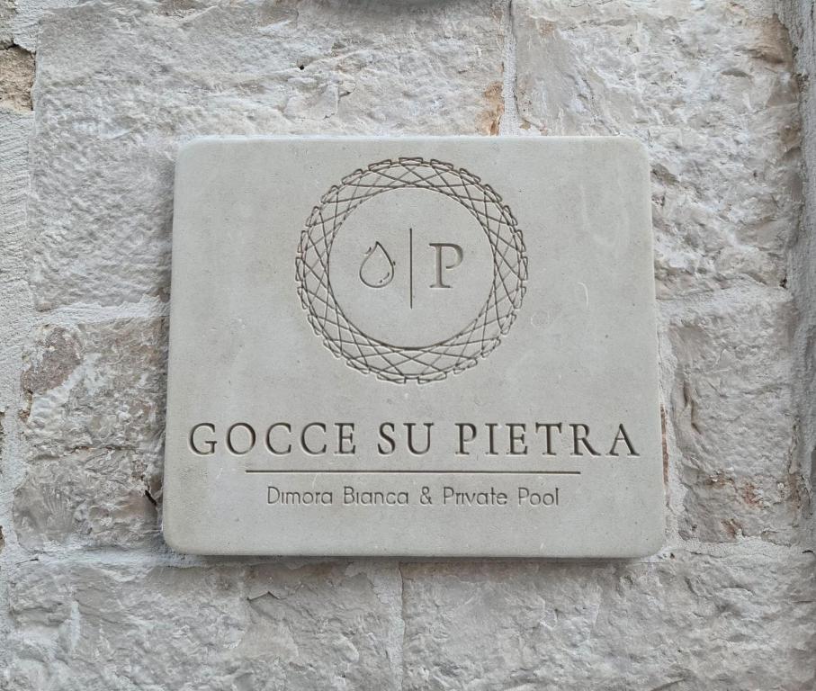 a stone sign on a brick wall with the name of goggle suteria at Gocce su Pietra in Sannicandro di Bari