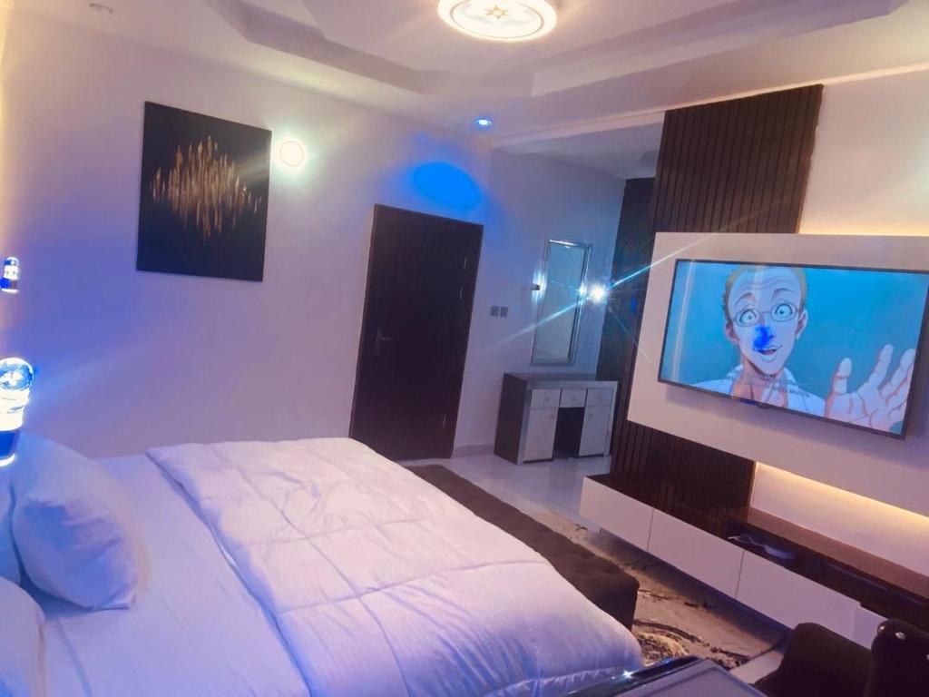 a bedroom with a bed and a flat screen tv at Sheylex Apartments in Idogwari