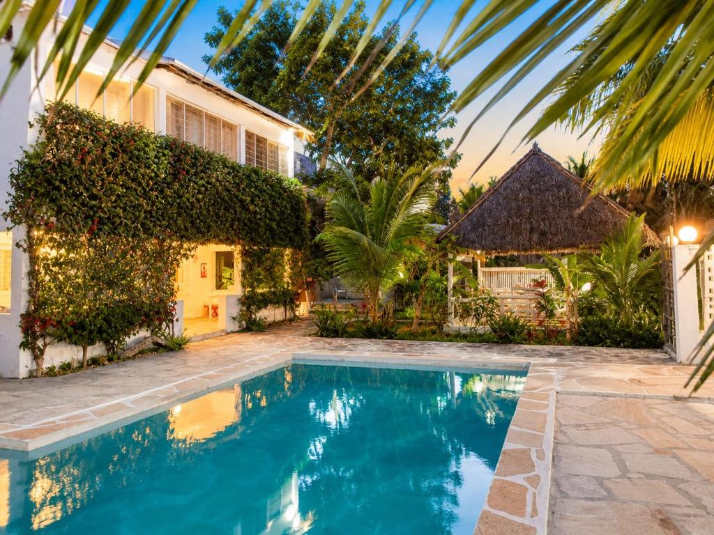 a villa with a swimming pool in front of a house at Hide Away Villa in Watamu