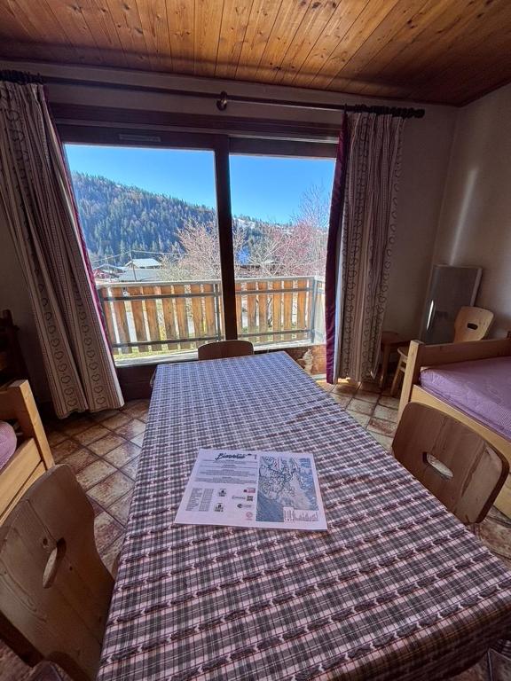 a room with a table with a view of a balcony at Studio Ban rouge, Chez Francine in Notre-Dame-de-Bellecombe
