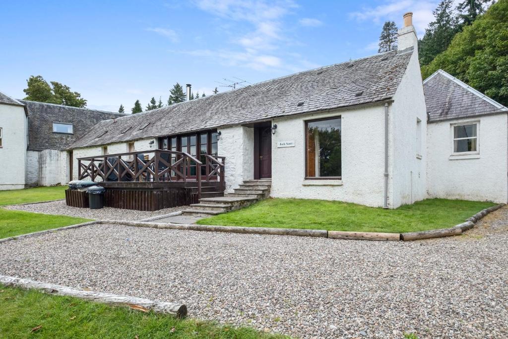 a white house with a gravel driveway at Jock Scott Cottage in Dunkeld