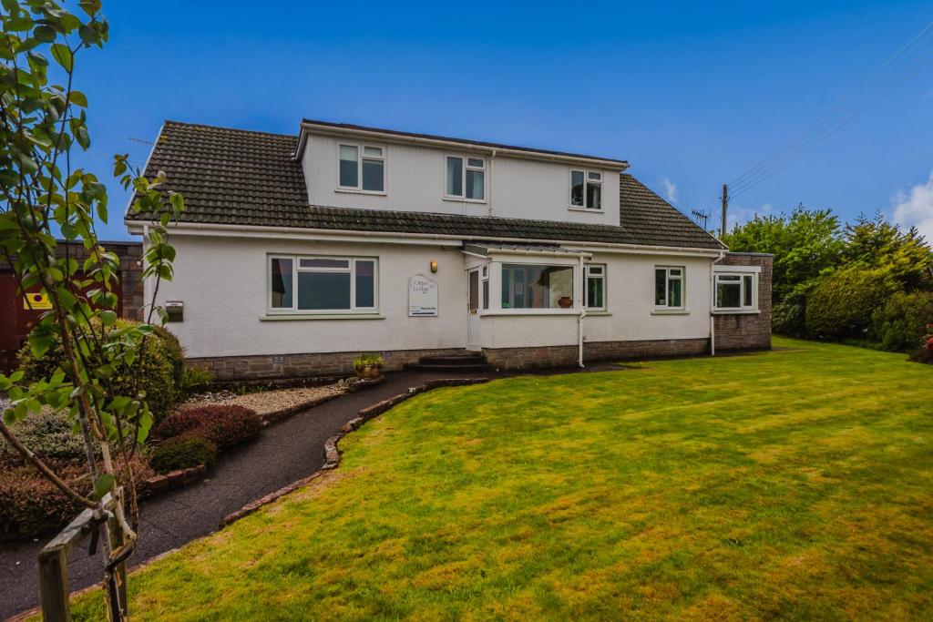 a white house with a large yard at The Otter Lodge in Broadford