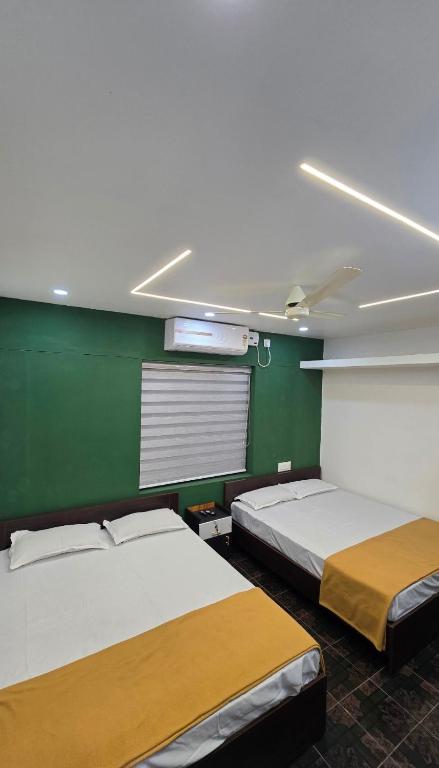 two beds in a room with a green wall at S J RESiDENCY in Trivandrum
