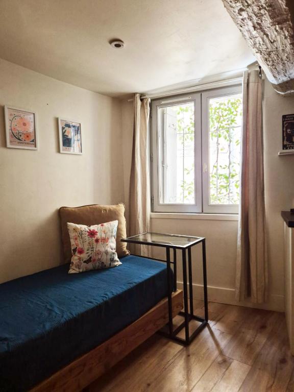 a room with a bed and a table and a window at 17m2 Flower studio dans le centre historique Ecusson in Montpellier