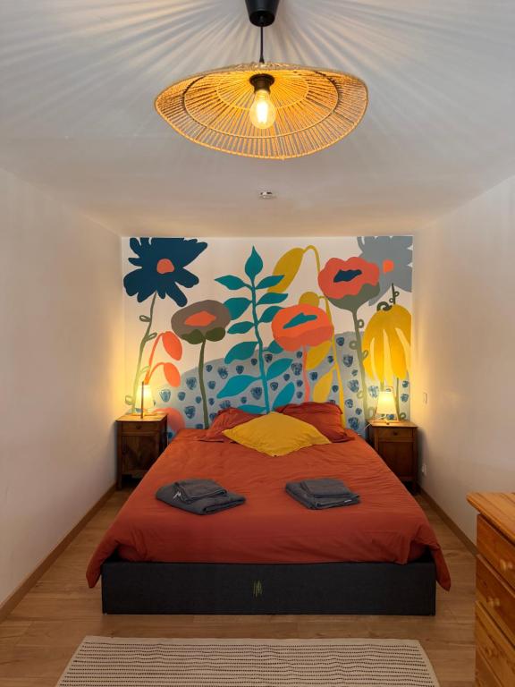 a bedroom with a bed with a flower mural on the wall at Joli logement au calme in Vésonne