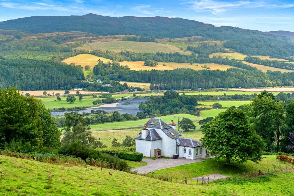 a house on a hill in a field with a river at Castle Peroch in Dunkeld